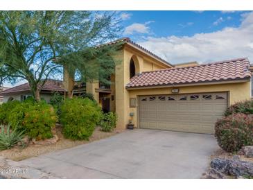 Tan two-story home with a tile roof, two-car garage, and nicely landscaped yard at 7846 E Mackenzie Dr, Scottsdale, AZ 85251