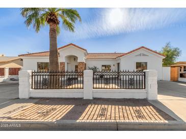 Remodeled home with a white exterior, landscaped front yard, and a new fence at 9821 E University Dr, Mesa, AZ 85207