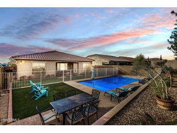 Inviting backyard oasis featuring a sparkling pool, patio furniture, and lush landscaping at 25891 N 104Th Dr, Peoria, AZ 85383