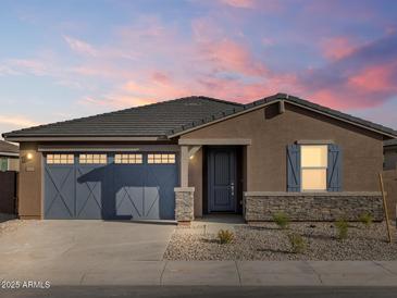 Charming single-story home showcasing a stylish blue garage door and complementary stone accents at 37358 W San Clemente St, Maricopa, AZ 85138