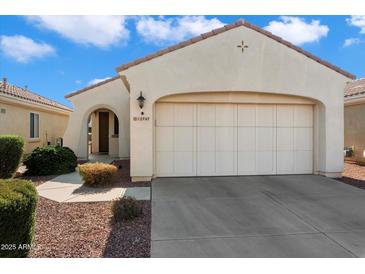 Beige house with a two-car garage and landscaped front yard at 12947 W Chapala Dr, Sun City West, AZ 85375