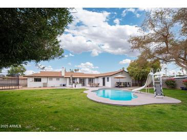 Inviting backyard oasis featuring a sparkling pool, grassy lawn, and patio entertaining area at 1624 W Lawrence Rd, Phoenix, AZ 85015