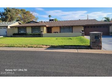 Ranch style home with landscaped lawn, attached garage, and driveway at 1707 E Mclellan Blvd, Phoenix, AZ 85016