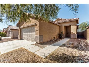 Tan house with tile roof, two-car garage, and landscaped front yard at 19422 N Smith Dr, Maricopa, AZ 85139