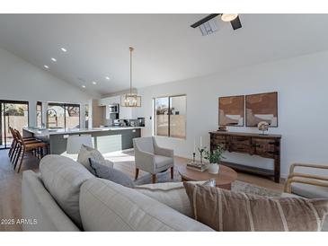 Bright living room features vaulted ceilings, hardwood floors, and neutral color palette at 2513 N 90Th Ln, Phoenix, AZ 85037