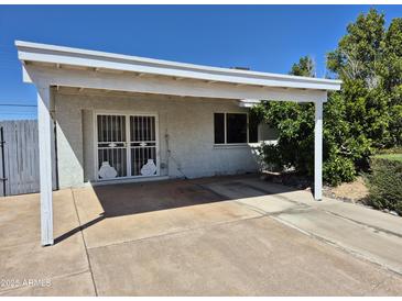 Sun-shaded carport area with grated doorway and mature landscaping for added privacy and appeal at 6126 W Earll Dr, Phoenix, AZ 85033