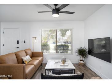 Spacious living room with a leather sofa, coffee table, and large TV at 725 E Vaughn Dr, Tempe, AZ 85283