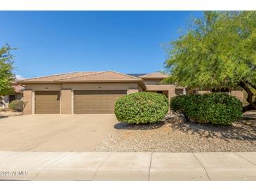 Three-car garage and front yard with drought-tolerant landscaping at 17311 N Havasupai Dr, Surprise, AZ 85374