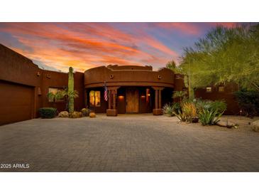 Exterior of a Southwestern style home with a brick driveway and desert landscaping at sunset at 25555 N Wrangler Rd, Scottsdale, AZ 85255