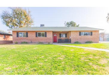 Brick ranch home with a well-manicured lawn and red front door at 5201 N 18Th Pl, Phoenix, AZ 85016