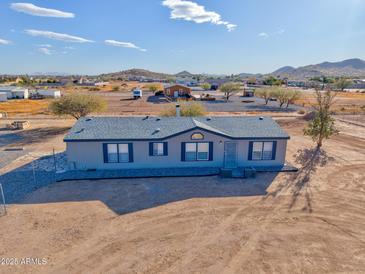 Single-level manufactured home with a large yard, situated on a spacious lot at 10991 W Hilltop Dr, Casa Grande, AZ 85193