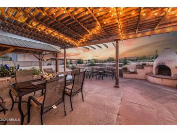 Outdoor patio with dining area, fireplace, and string lights at 6052 N 183Rd Ave, Waddell, AZ 85355