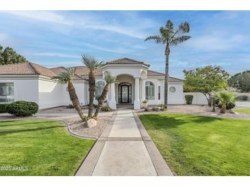 Elegant single-story home boasts a lush lawn, tile roof, and inviting wrought iron accented front entry at 4135 E Hale Cir, Mesa, AZ 85205