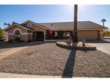 Tan house with tile roof, landscaping, and a two-car garage at 14731 W Trading Post Dr, Sun City West, AZ 85375