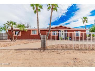 Reddish-brown single story home with a gated entrance and palm trees in the front yard at 22183 N 178Th Ave, Surprise, AZ 85387