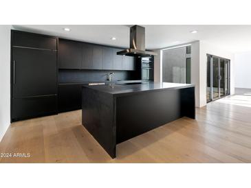 Modern kitchen with sleek black cabinetry, large island, and high-end appliances at 4825 N 72Nd Way, Scottsdale, AZ 85251