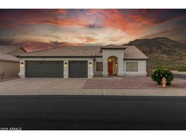 Two-story house with a three-car garage, landscaping, and mountain views at 6102 W Whispering Wind Dr, Glendale, AZ 85310