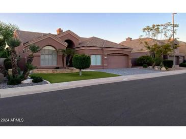 Charming single-story home featuring a neutral color, tile roof, manicured lawn, and two-car garage at 9672 E Davenport Dr, Scottsdale, AZ 85260