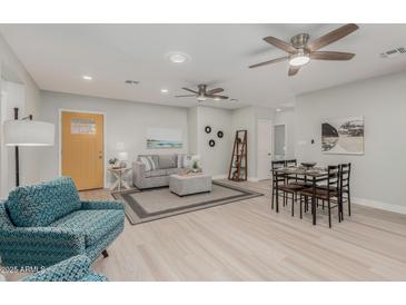 Open living room and dining area with light wood floors and ceiling fans at 1022 E Mariposa St, Phoenix, AZ 85014