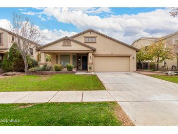 Single-story home with a tan facade, landscaped lawn, and a two-car garage at 4041 E Lexington Ave, Gilbert, AZ 85234