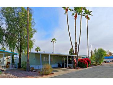 Mobile home with covered porch, landscaped yard, and mature palm trees at 9501 E Broadway Rd # 140, Mesa, AZ 85208