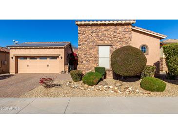 Tan two-story house with stone accents, two-car garage, and nicely landscaped yard at 17770 W Cottonwood Ln, Goodyear, AZ 85338