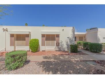 Front view of a light beige house with brown shutters and well-manicured landscaping at 17251 N Del Webb Blvd, Sun City, AZ 85373