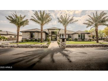 Stunning curb appeal! This property features a two-story home with a stone facade and palm trees at 18145 W Rancho Dr, Litchfield Park, AZ 85340