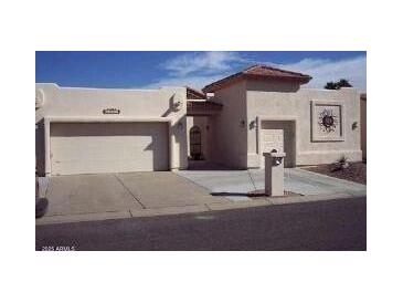 Tan two-car garage stucco home with a Spanish-style tile roof at 26409 S Moonshadow Dr, Sun Lakes, AZ 85248