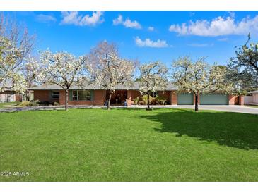 Charming red brick home featuring a lush green lawn and flowering trees under a bright blue, sunny sky at 8031 N 14Th Ave, Phoenix, AZ 85021