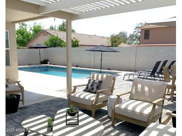 Inviting backyard with sparkling pool, patio furniture, and pergola at 9207 W Highland Ave, Phoenix, AZ 85037