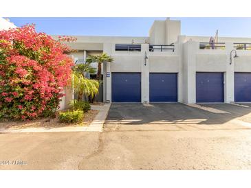 Condo exterior featuring a walkway, attached garages, and vibrant landscaping at 902 W Glendale Ave # 203, Phoenix, AZ 85021