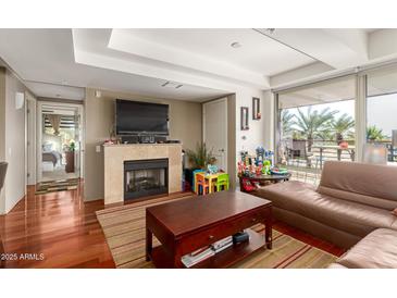 Living room with fireplace, hardwood floors, and brown leather sectional at 7167 E Rancho Vista Dr # 4011, Scottsdale, AZ 85251