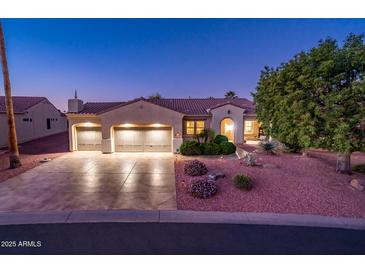 Three-car garage, desert landscaping, and well-lit driveway at 12928 W Santa Ynez Dr, Sun City West, AZ 85375