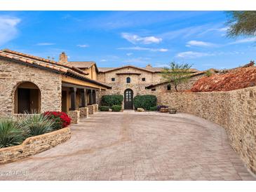Stately stone home featuring a beautiful brick driveway, mature landscaping, and a classic tiled roof at 16117 E Shooting Star Trl, Fountain Hills, AZ 85268