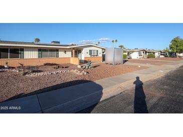 Ranch-style home with brick facade and landscaped front yard at 10620 W Clair Dr, Sun City, AZ 85351