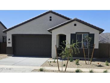 Charming single-story home featuring neutral stucco, a dark brown garage door, and desert landscaping at 22319 W Monona Ln, Surprise, AZ 85387