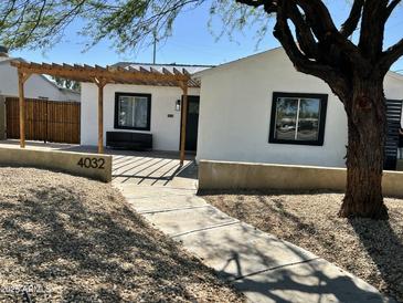 Charming single-story home featuring stucco walls, black-framed windows, and a wooden pergola for shaded outdoor seating at 4032 N 11Th Ave, Phoenix, AZ 85013