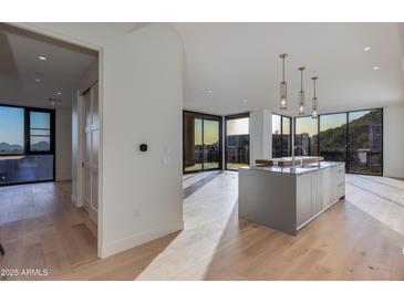 Modern kitchen with stainless steel island, hardwood floors, and floor to ceiling windows with mountain views at 5000 N Camelback Ridge Dr # 301, Scottsdale, AZ 85251