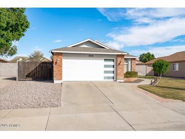 Brick home with a white garage door and well-manicured lawn at 8828 E Des Moines St, Mesa, AZ 85207