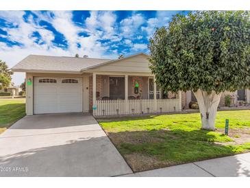 Cute ranch house with carport, covered porch, and a large tree in the front yard at 9245 N 109Th Dr, Sun City, AZ 85351