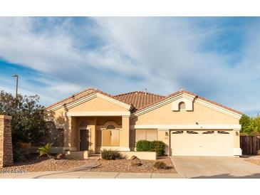 One-story house with tan exterior, landscaped yard, and two-car garage at 1964 S Marble St, Gilbert, AZ 85295