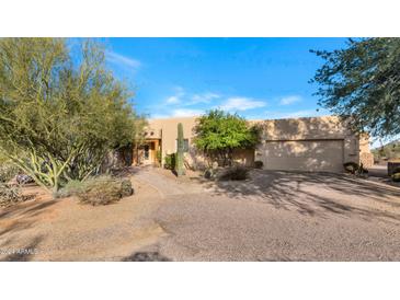 Desert landscape surrounds this one-story home with stucco exterior and attached garage at 5743 E Windstone Trl, Cave Creek, AZ 85331