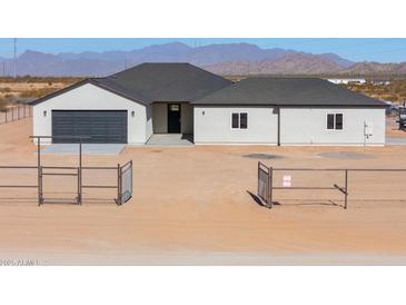 New single-story home with a modern design, two-car garage, and gated entrance at 57968 W Fulcar Rd, Maricopa, AZ 85139