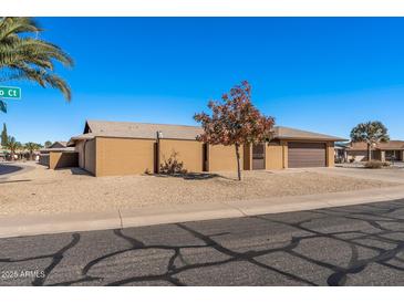 Tan brick single-story home with a brown garage door and desert landscaping at 9714 W Rodeo Ct, Sun City, AZ 85373