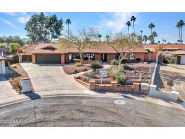 Single-story home with desert landscaping, large driveway, and attached garage at 215 E Marconi Ave, Phoenix, AZ 85022