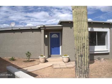 Ranch style home with blue front door, landscaping, and a saguaro cactus at 4124 N 105Th Ln, Phoenix, AZ 85037