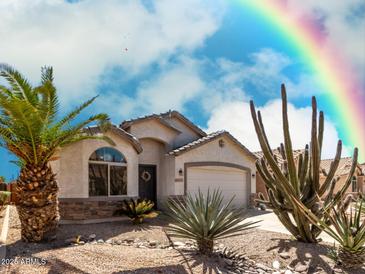 Charming single-story home featuring desert landscaping with a palm tree and a rainbow in the background sky at 45579 W Rainbow Dr, Maricopa, AZ 85139