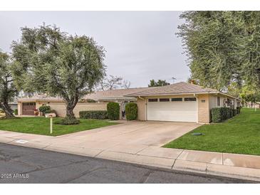 Charming single-story home with a well-maintained yard, mature trees, and two-car garage at 18852 N Aztec Dr, Sun City, AZ 85373