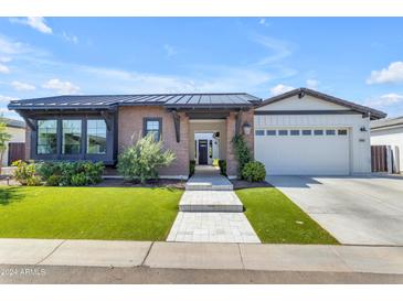 Craftsman style home with brick facade, attached two-car garage, and well-manicured lawn at 21961 E Via De Arboles St, Queen Creek, AZ 85142